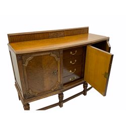 Early 20th century carved oak sideboard, the raised back carved with scroll work over angled moulded top, enclosed by three doors carved with trailing foliage and berries, the central cupboard fitted with four drawers, on baluster carved supports joined by moulded stretchers