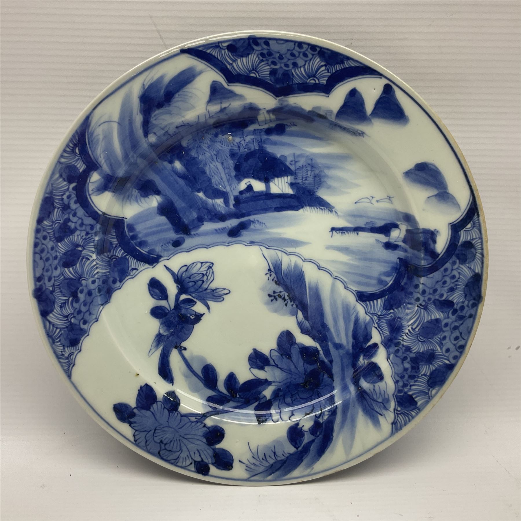 Japanese Meiji period Arita blue and white plate, of circular form, painted with riverside landscape and bird upon flowering branch, with character mark beneath, D24.5cm, together with two 18th century Chinese blue and white plates, each painted with floral design, each approximately D22.5cm
