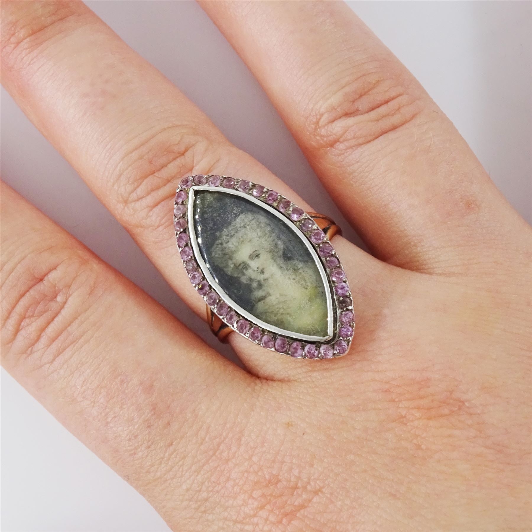 18th / 19th century gold and silver paste stone set portrait ring, the navette bezel set with a miniature of a woman on ivory, under a glazed panel, within a pink paste border and trifurcated shoulders. This lot has been registered for sale under Section 10 of the APHA Ivory Act