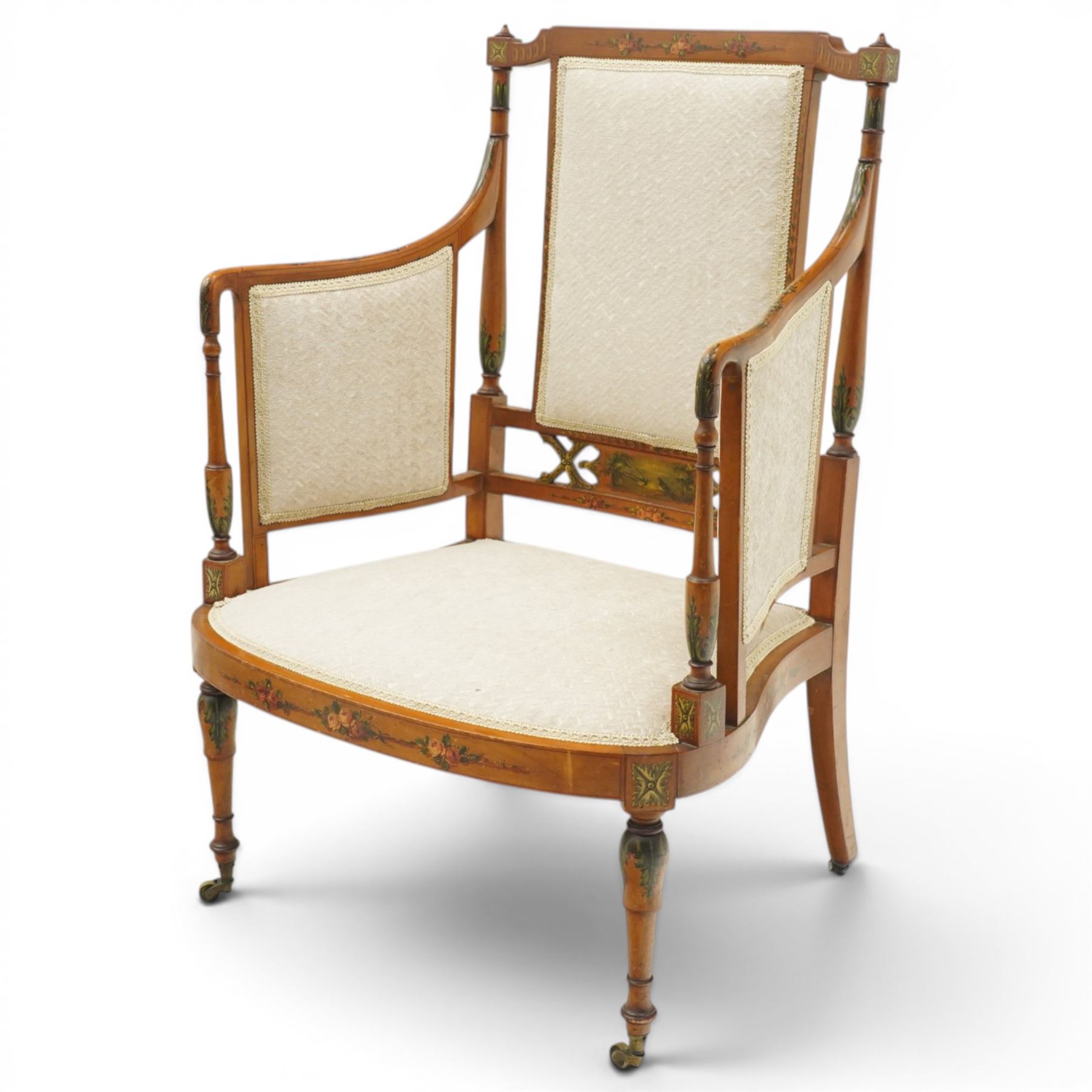 Pair of Victorian Sheraton Revival painted satinwood armchairs, the cresting rail painted with trailing floral bouquets flanked by illusion arcade motifs, over a cameo back and sides with acanthus painted swell-turned uprights, the lower back rail decorated with a bird scene and flanking pierced foliate design, upholstered in ivory fabric, raised on turned supports with further acanthus leaf paintwork, terminating to brass castors