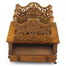 Victorian walnut Canterbury, scroll pierced divisions with turned carrying handles above a frieze drawer with knob handles, raised on turned legs terminating in brass castors