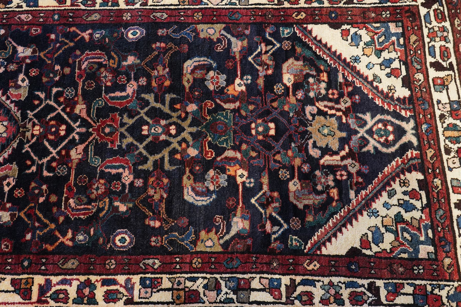 North West Persian Hamadan hand-knotted runner, indigo field with an all-over herati inspired lattice issuing from a central axis with stylized palmettes, rosettes and angular vinery, enclosed by stepped triangular spandrels with ivory reserves, broad ivory main border of stylized flowers and geometric devices, flanked by reciprocal guard stripes, cotton fringe ends 
