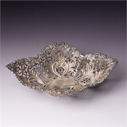 Edwardian silver oval dressing table box, the hinged cover embossed with angel heads W10cm London 1902 Maker William Comyns & Sons and an Edwardisn pierced silver oval sweetmeat basket L18cm Sheffield 1907 Maker James Dixon & Sons Ltd