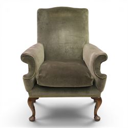 Pair of Georgian style wing armchairs, upholstered in green velvet, each with shaped wing backs, padded scroll arms and loose seat cushions, raised on cabriole supports terminating in pad feet, one with tasselled fringe