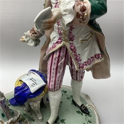 20th century Naples figure group, modelled as a seated female figure playing the lute seated, before a male figure stood holding a sheet of music, each in period dress, upon an oval base with gilt heightened scroll edge, with crowned N mark beneath, H31.5cm L33cm
