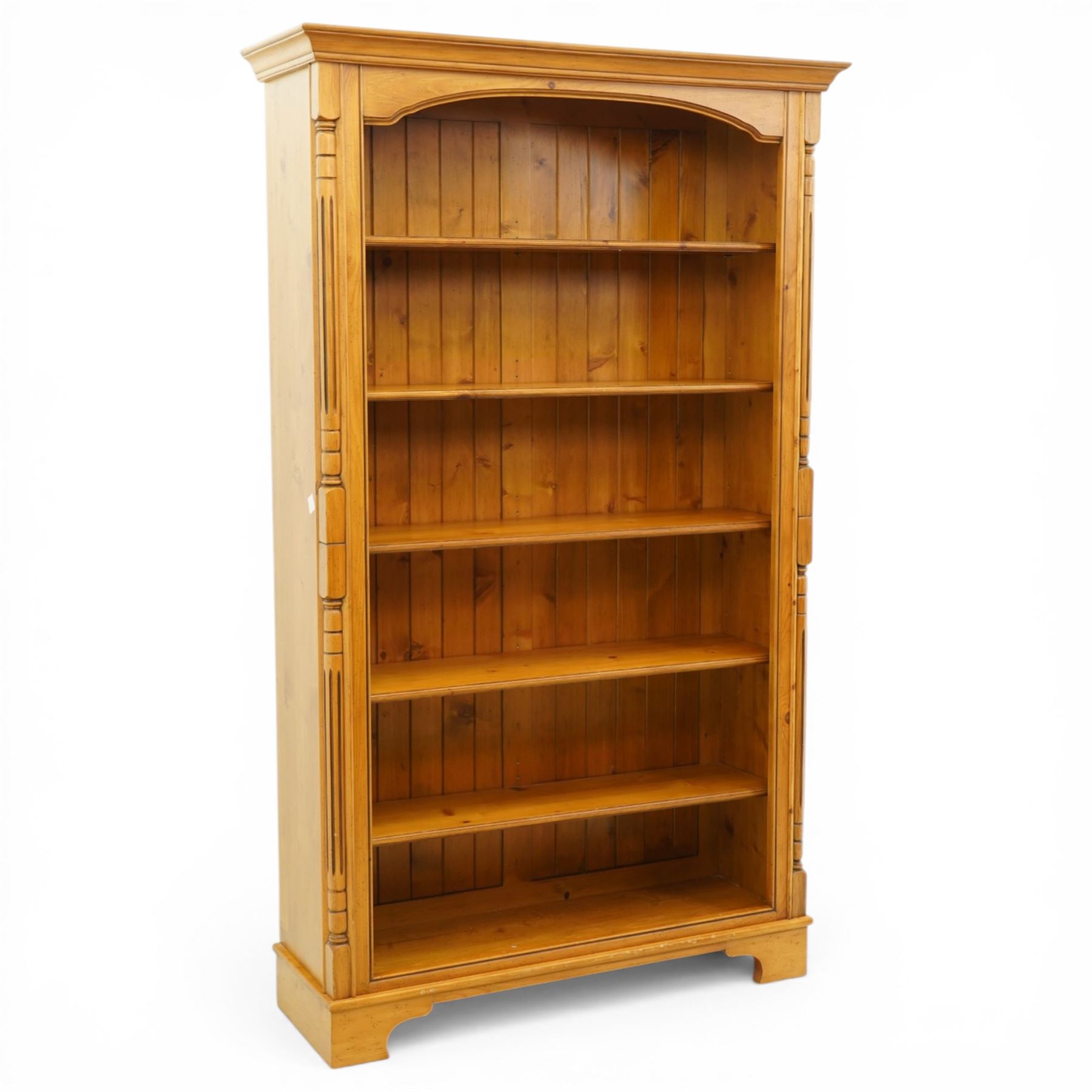 Late 20th century traditional waxed pine open bookcase, moulded cornice above a shaped frieze, open front with fixed shelves and boarded back, flanked by fluted pilasters
