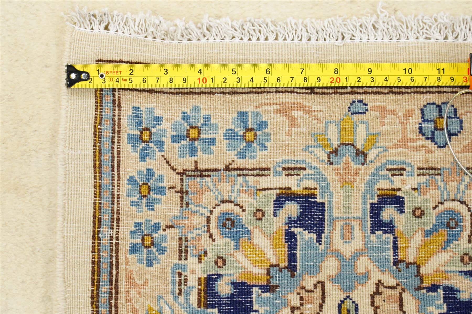 South East Persian Kirman hand-knotted carpet, ivory field with central floral medallion in tones of cobalt and pale blue, issuing scrolling vinery and palmettes, conforming spandrels, main border with scrolling foliage and stylized palmettes, framed by multiple guard borders, with cotton fringe ends 