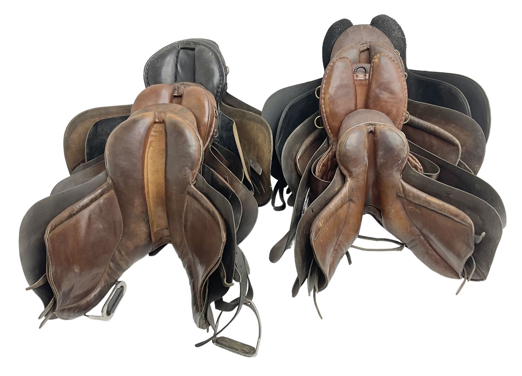 Collection of nine saddles, mainly havana leather to include a racing saddle and a Goodwin saddle, some with stirrups and leathers 