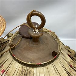 Trench Art shell lamp upon a stepped circular base, together light fitting with an umbrella shade depicting a hunting scene and a wicker lamp shade