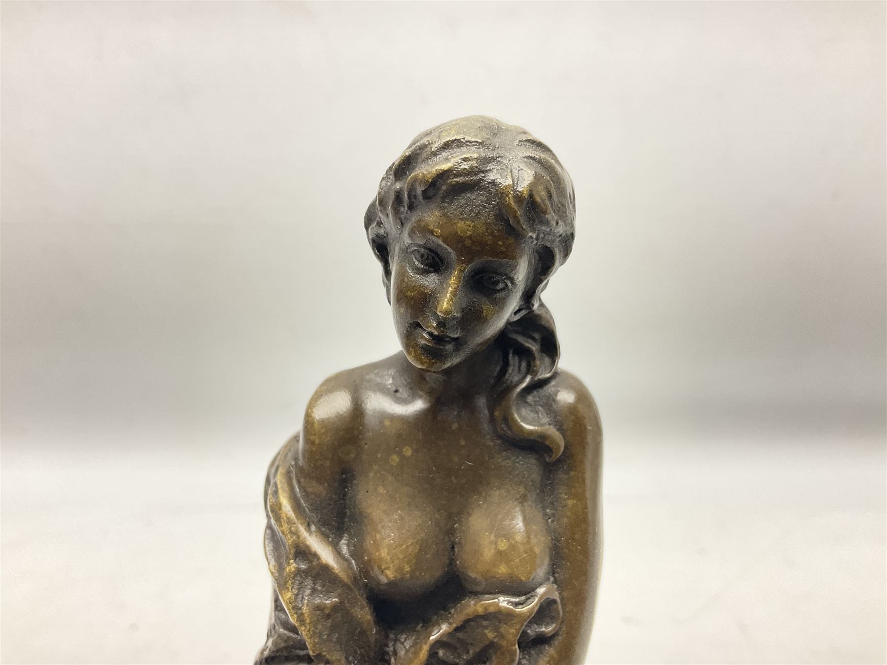 Art Deco style bronze modelled as a female figure seated upon a chair holding an apple, after 'Pierre Collinet', H28cm