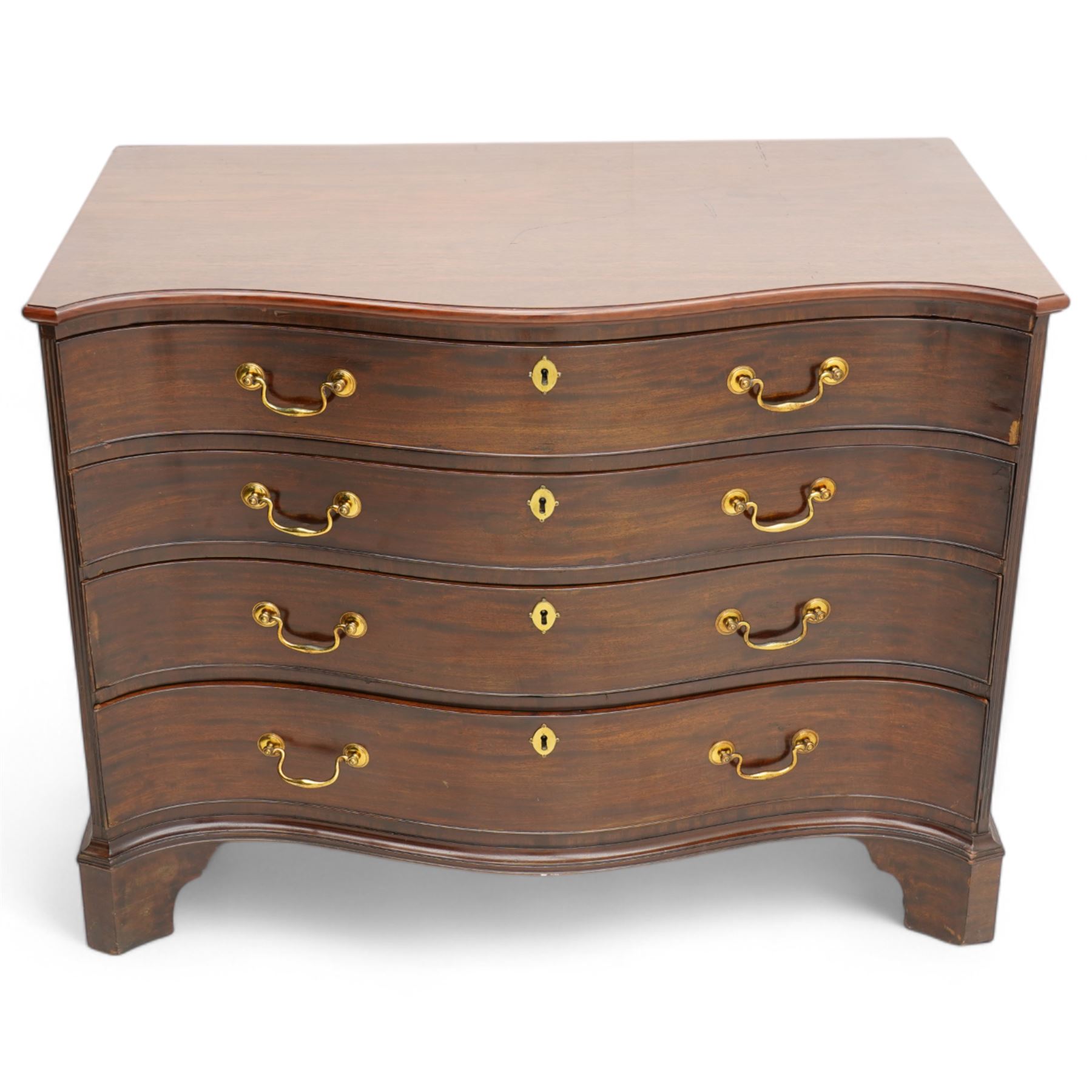 George III mahogany serpentine chest, moulded top over four cock-beaded drawers, the top drawer fitted with baize lined slide opening to reveal divisions,  enclosed by canted and fluted upright corners, the drawer fronts fitted with brass swan neck handles and circular plates with oval escutcheons, lower moulded edge over bracket feet, on lignum vitae castors