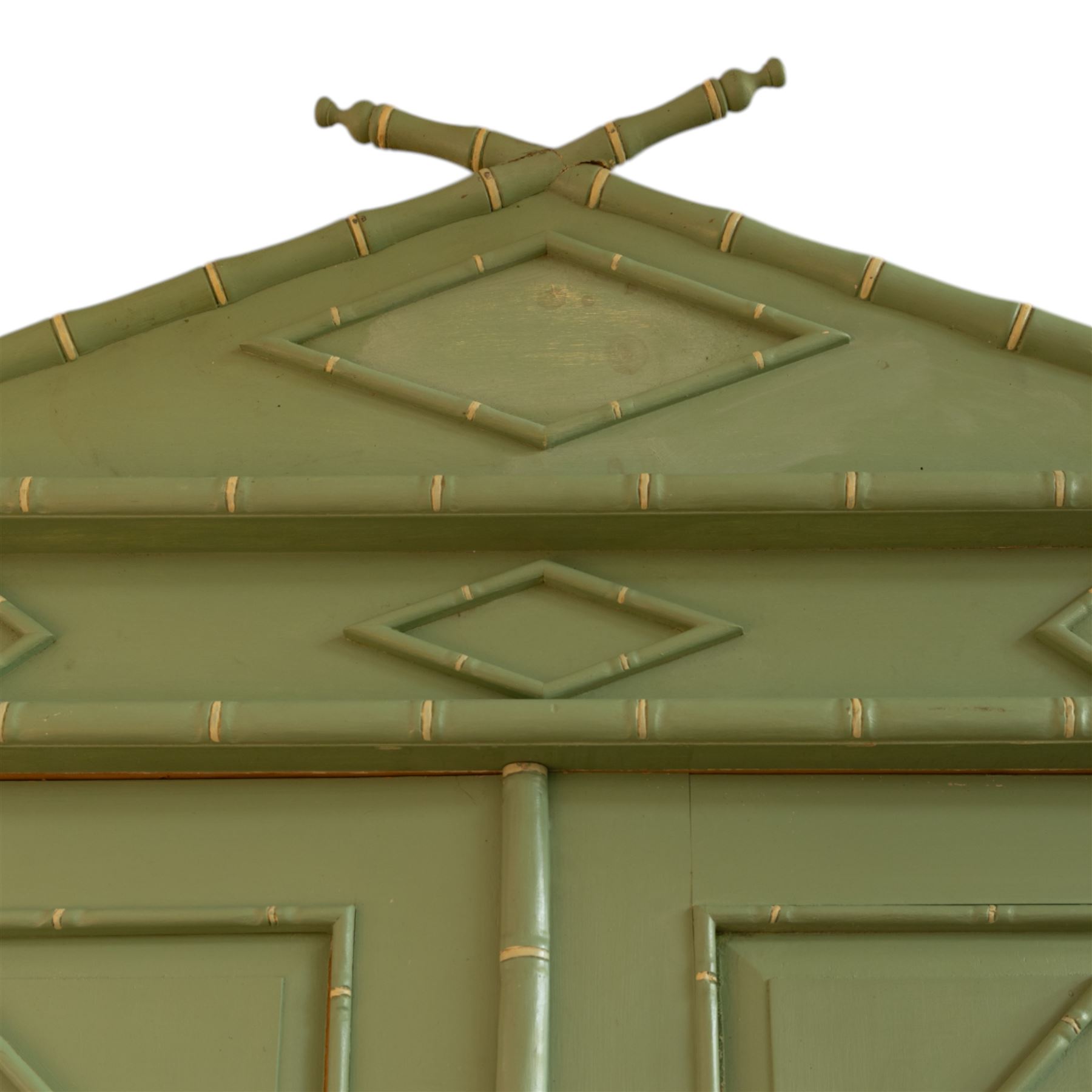 Regency design chinoiserie painted pine armoire, finished in sage green with carved simulated bamboo mouldings, projecting pediment with central lozenge panel, frieze decorated with small lozenges  surmounted by crossed finials, twin doors with diamond-shaped mouldings, interior with hanging cupboard, framed by full-length faux bamboo pilasters, above lower section with two short drawers on post feet 
