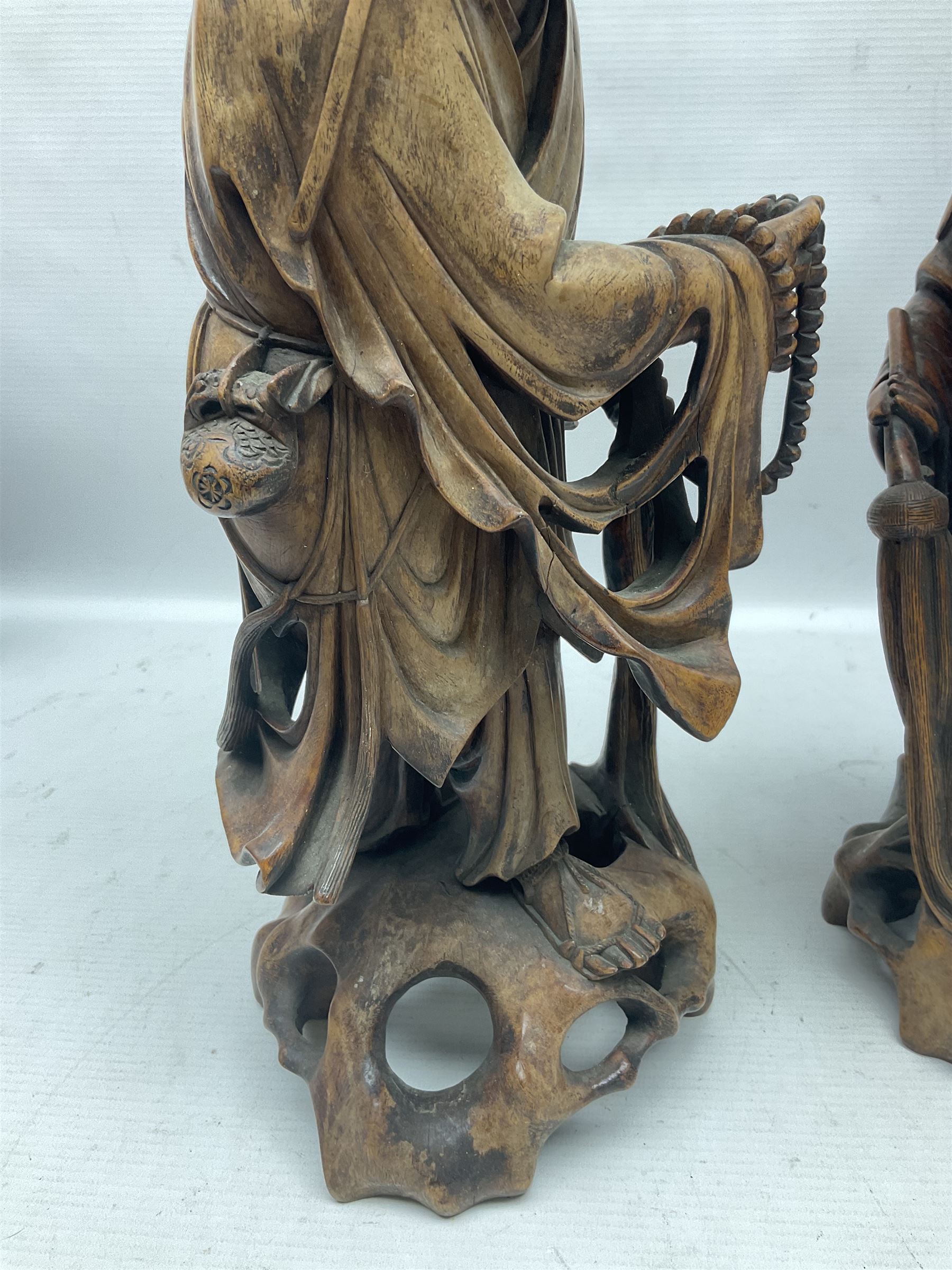 Pair of Japanese carved wooden figures, modelled as merchants in traditional dress, upon pierced naturalistic bases, tallest H39cm