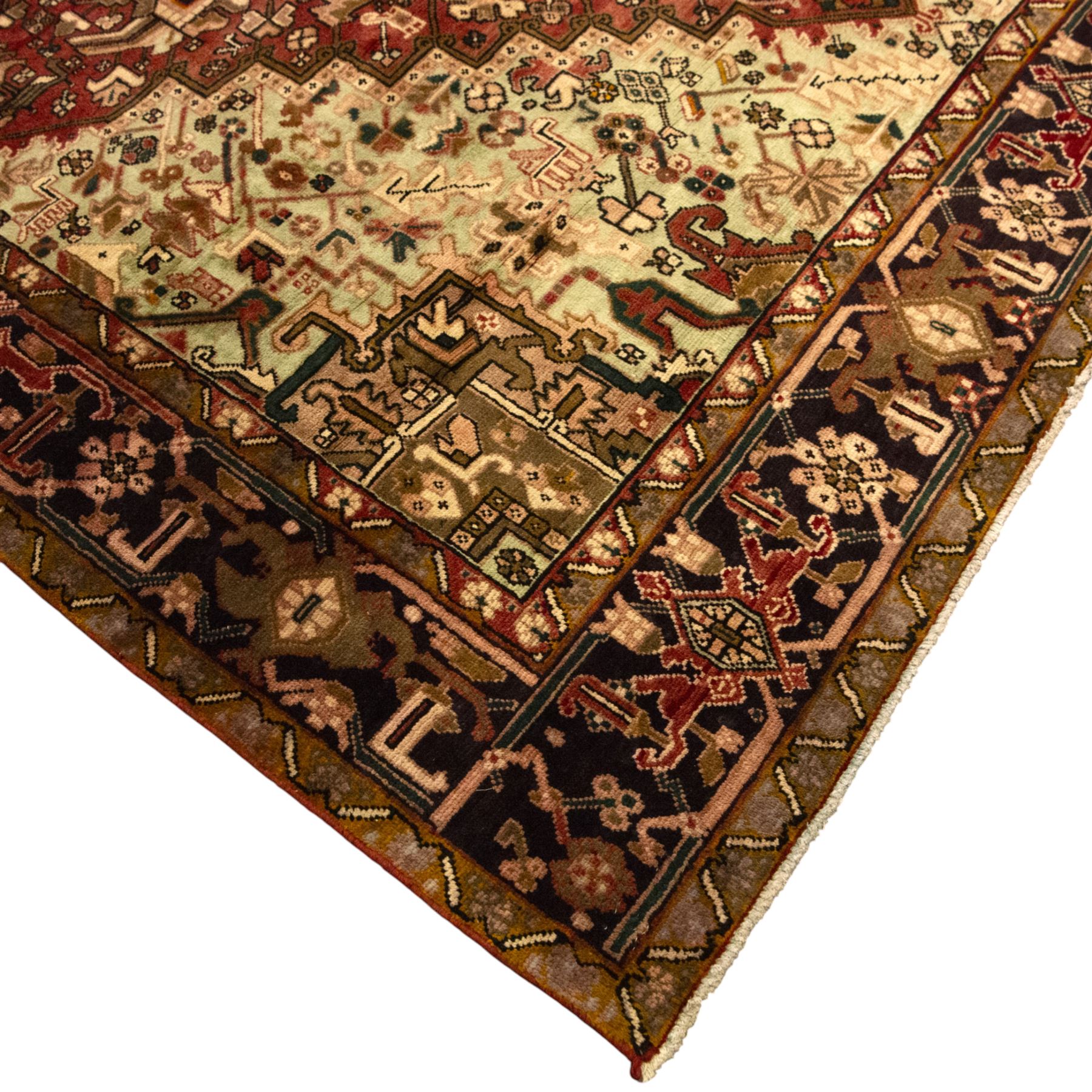 Northwestern Persian Heriz carpet, crimson ground and soft green field, with bold terracotta stepped medallion with angular spandrels and geometric motifs within a broad palmette and vine border 