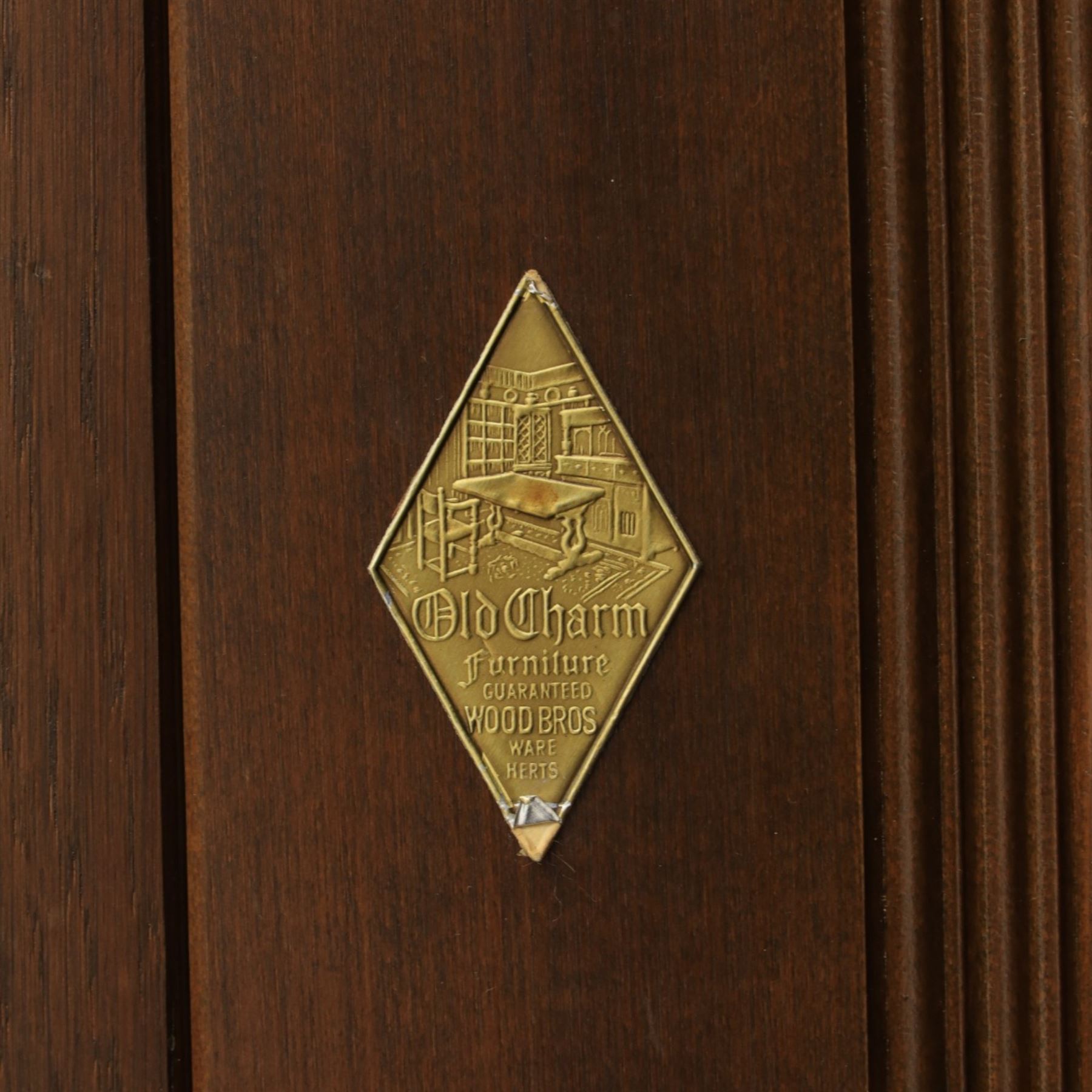Old Charm - carved oak bar with three bar stools and associated Old Charm drinks cabinet, carved top with channels for glassware beneath, bar surface above glazed panels, shelves for glassware to the back, associated Old Charm drinks cabinet with fall front linenfold carving, above twin doors with shelved interior