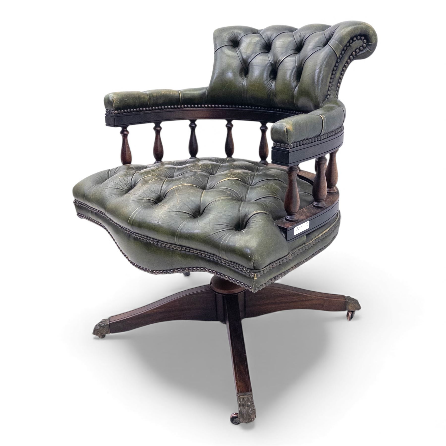 Mid 20th century buttoned green leather office chair, the curved back and arms over a circular frame with turned spindle supports, on a revolving base with four splayed legs and brass castors