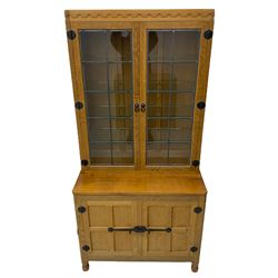 'Mouseman' oak display cabinet on cupboard, raised cabinet enclosed by two lead glazed doors, adzed oak top over double panelled cupboard, fitted with ironwork and carved with mouse signature, by Robert Thompson of Kilburn