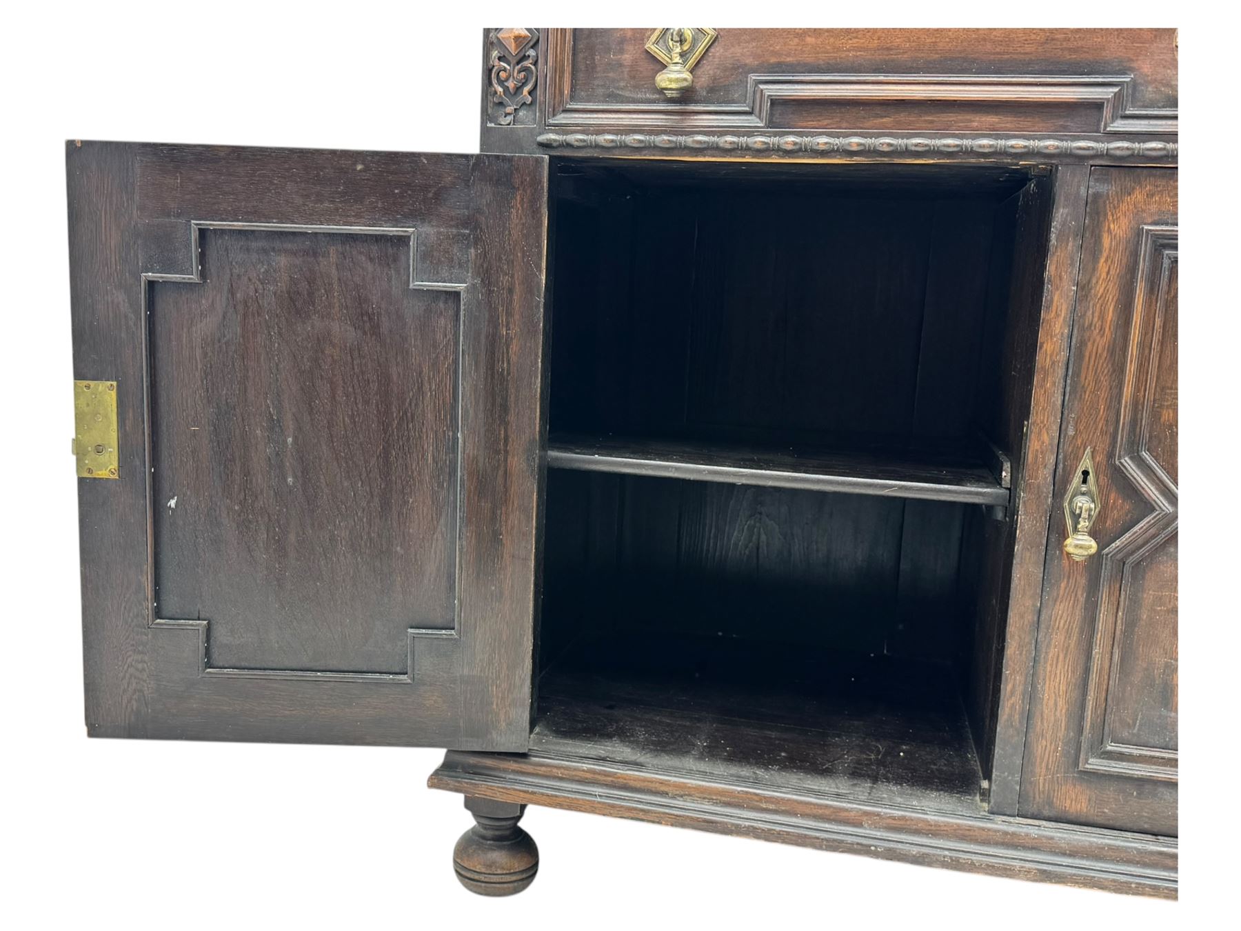 Jacobean-style oak dresser base with two frieze drawers above three cupboards with panelled and moulded decoration, fitted with drop handles, supported on bun feet, circa 1900