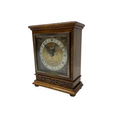 Elliot - oak cased 1950’s 8-day timepiece mantle clock, with a balance wheel movement wound and set from the rear, flat topped case with a carved panel raised on bun feet, square brass dial, silver chapter ring, spandrels and  decoratively engraved dial centre inscribed “Bracher & Sydenham, Reading”
