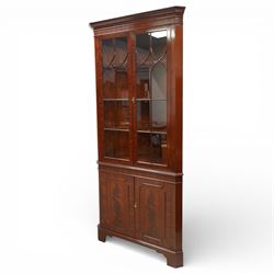 William Tillman - Early 20th century mahogany corner cabinet, the projecting moulded cornice with dentil detail over a glazed upper section enclosed by a pair of astragal glazed doors with Gothic arched tracery, the interior fitted with shaped shelves, above a moulded waist and a lower cupboard enclosed by two panelled doors with shaped fielded panels, raised on bracket feet