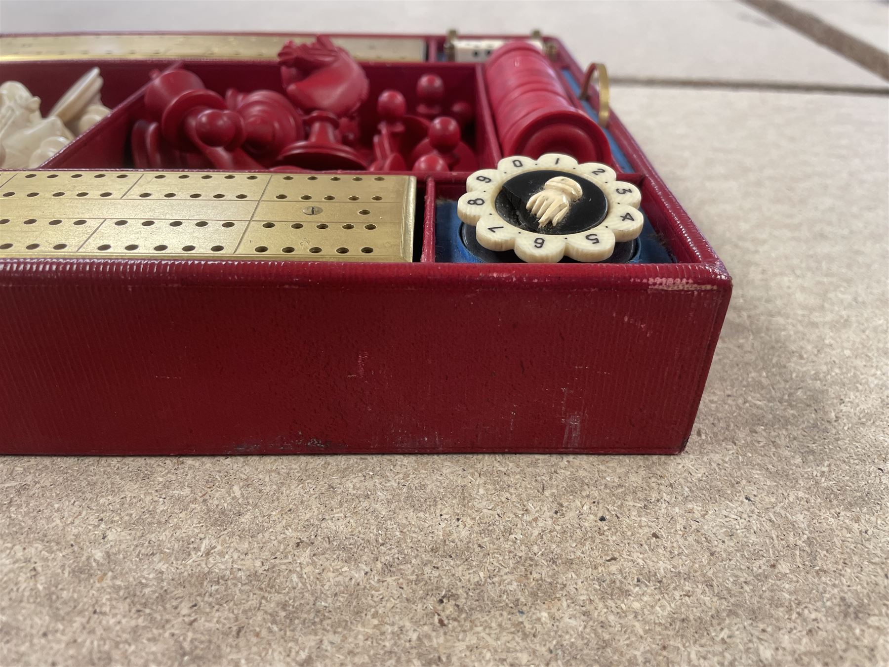 19th century walnut and brass bound games compendium box, painted to enhance the grain, of rectangular form, the hinged opening cover with rounded sides, central brass cartouche with engraved lion crest, and brass riveted straps, opening to reveal a red leather and blue silk lined compartmented interior, with fold-down games board, and lift-out tray containing playing cards, ebony turned dice towers, white and red stained bone draughts, and chess pieces, ivory dice, and ivory and ebony whist markers, and brass bezique board, cribbage board and markers, H15cm W32cm D24cm
This lot has been registered for sale under Section 10 of the APHA Ivory Act