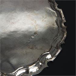 George II silver salver, of circular form with pie crust rim, with later floral and foliate decoration and presentation engraving to centre, upon three stepped feet, hallmarked William Peaston, London 1749, D30cm