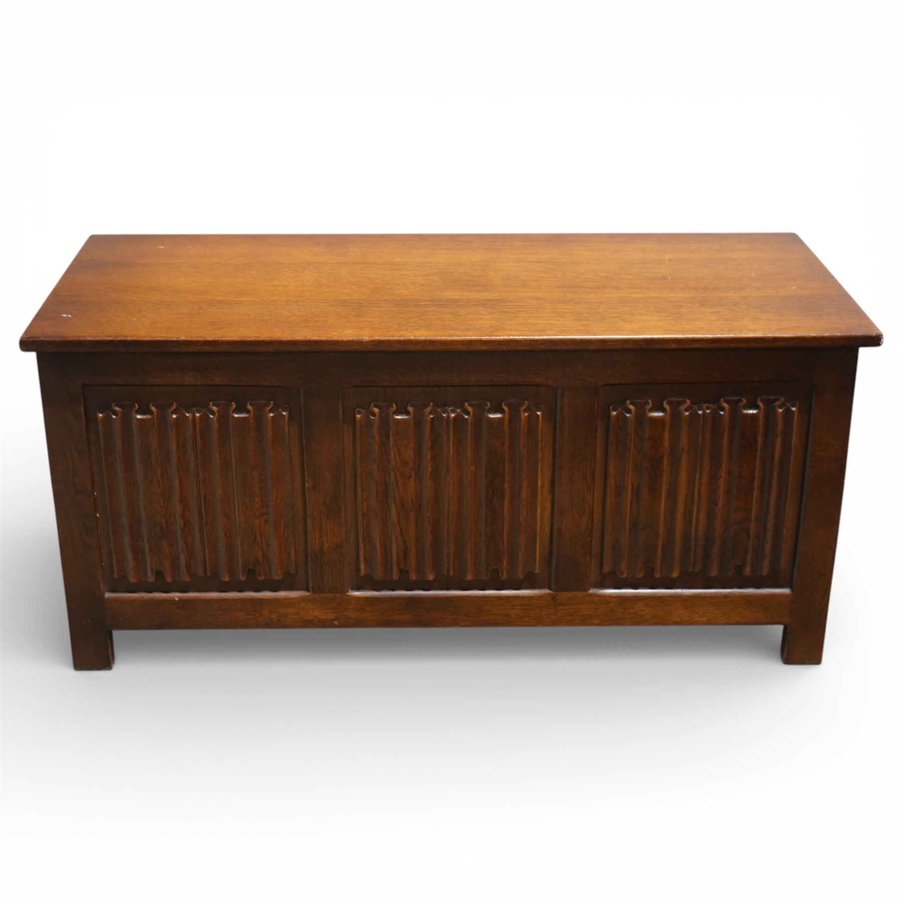 Late 20th century oak linenfold blanket box, with hinged rectangular top opening to a plain interior, the front carved with three linenfold panels, plain panelled sides, raised on stile supports