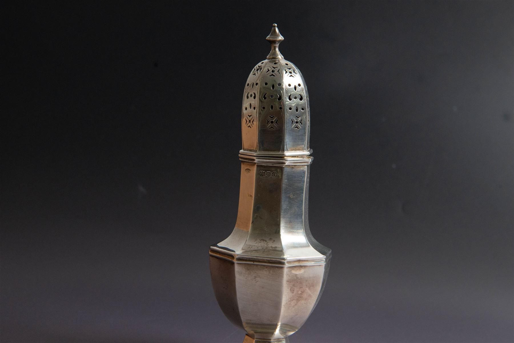 Edwardian silver sugar caster, of octagonal urn form, upon an octagonal foot, the removable pierced cover with urn finial, hallmarked Charles & George Asprey, London 1909, H21cm 