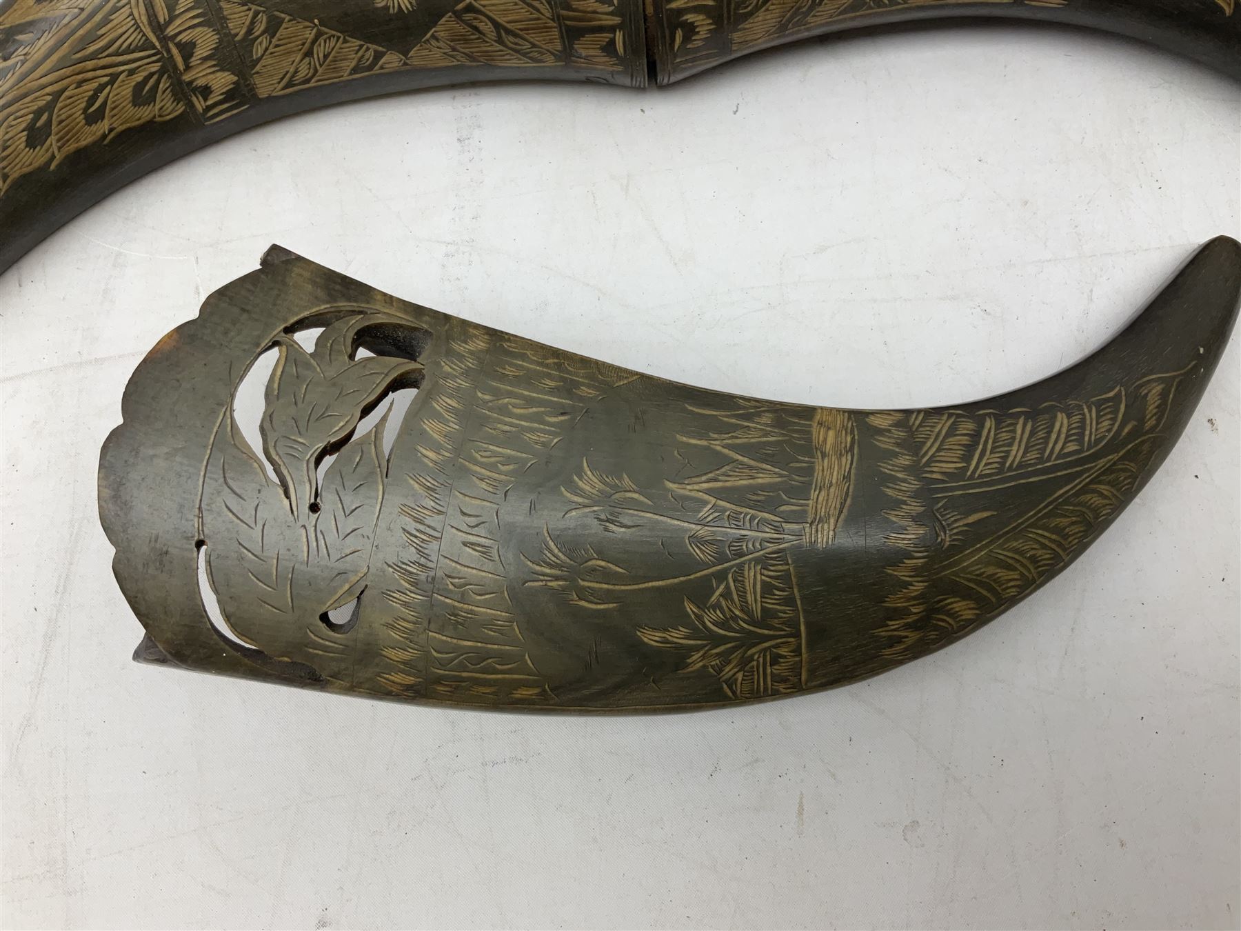 Carved water buffalo horn wall pocket, engraved with landscape scene with patterned borders with pierced foliate panel, together with a pair of horns with similar engraved decoration, L47cm
