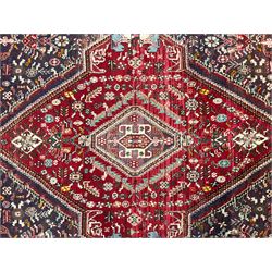 Persian Heriz crimson ground rug, field with large central lozenge surrounded by stylised plant motifs in a mauve background, guarded border with repeating foliage