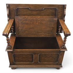 Early 20th century oak monks bench, panelled back converting to a table top, reeded armrests with barley twist uprights, hinged seat over panelled base supported on bun feet