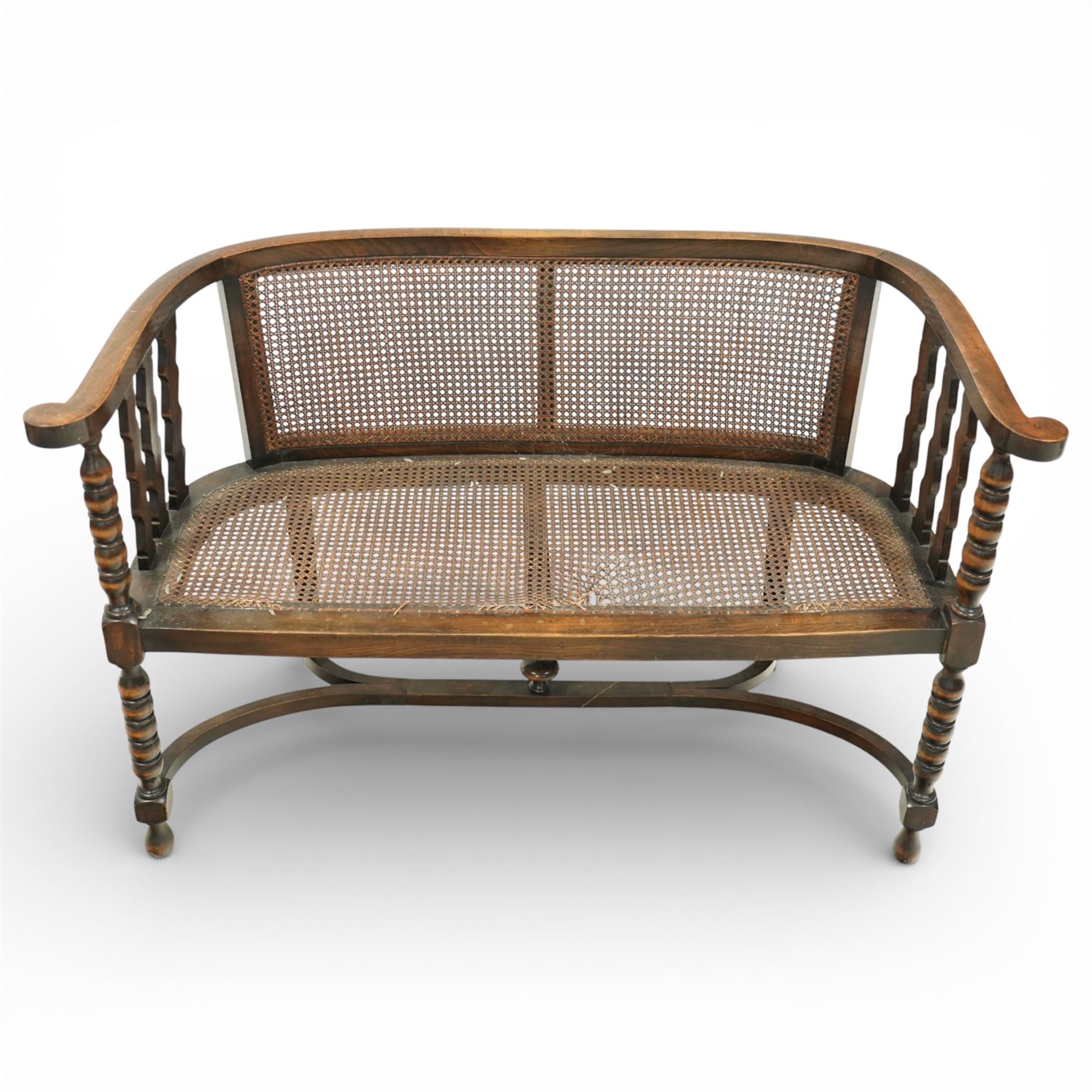 20th century bergère two seater settee, with shaped curved top rail and downswept arms, the back and seat fitted with woven cane panels, supported by turned uprights and legs united by a carolean stretcher 