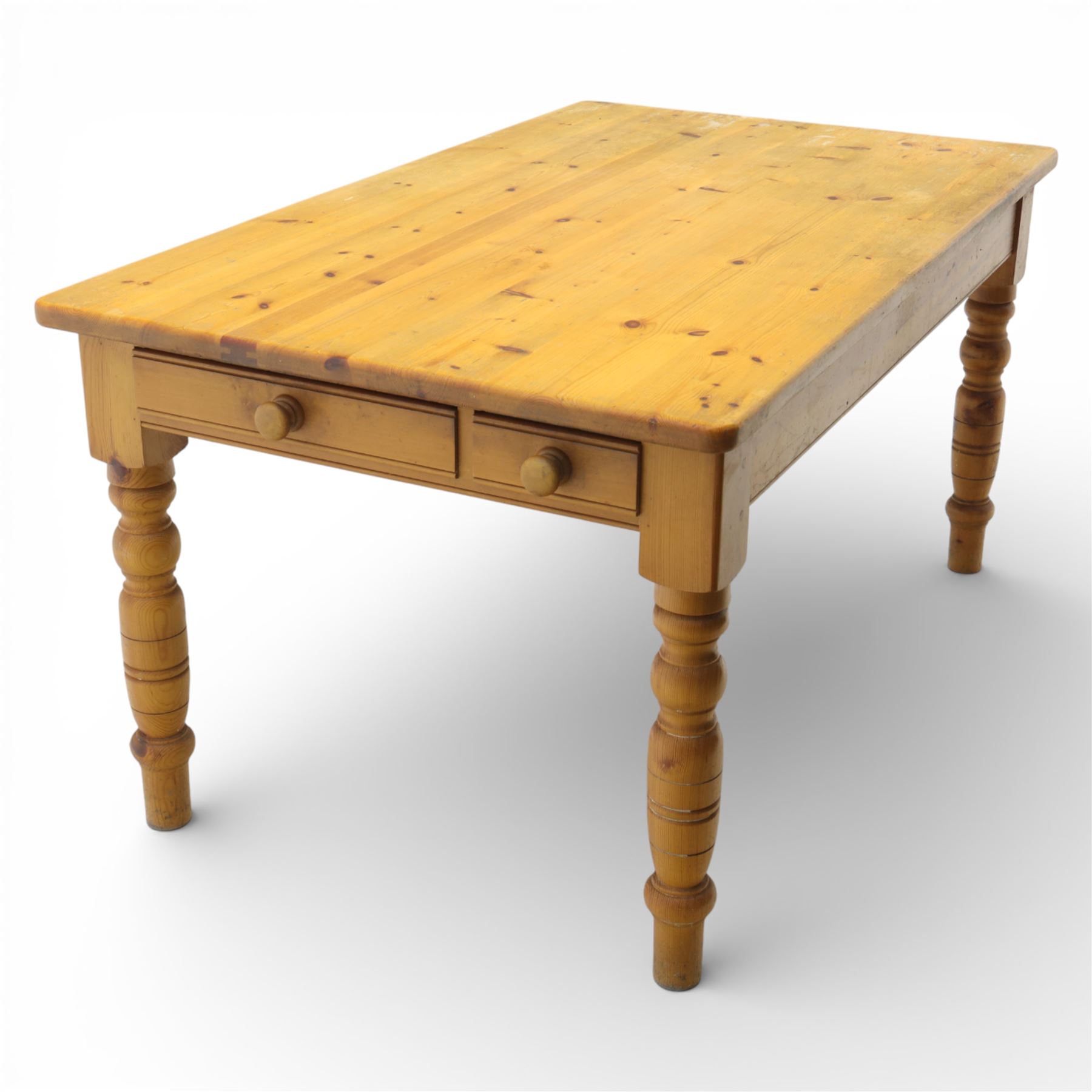 Late 20th century pine farmhouse dining table and four chairs, the rectangular plank top with rounded corners over two frieze drawers fitted with turned knob handles, raised on turned legs, the chairs with shaped ladder backs and turned finials, rush seats in a herringbone weave, on turned supports united by stretchers