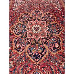 Antique Persian coral ground carpet, the large central floral pole medallion with extending foliate designs, the thick guarded indigo border with repeating flower heads and circles