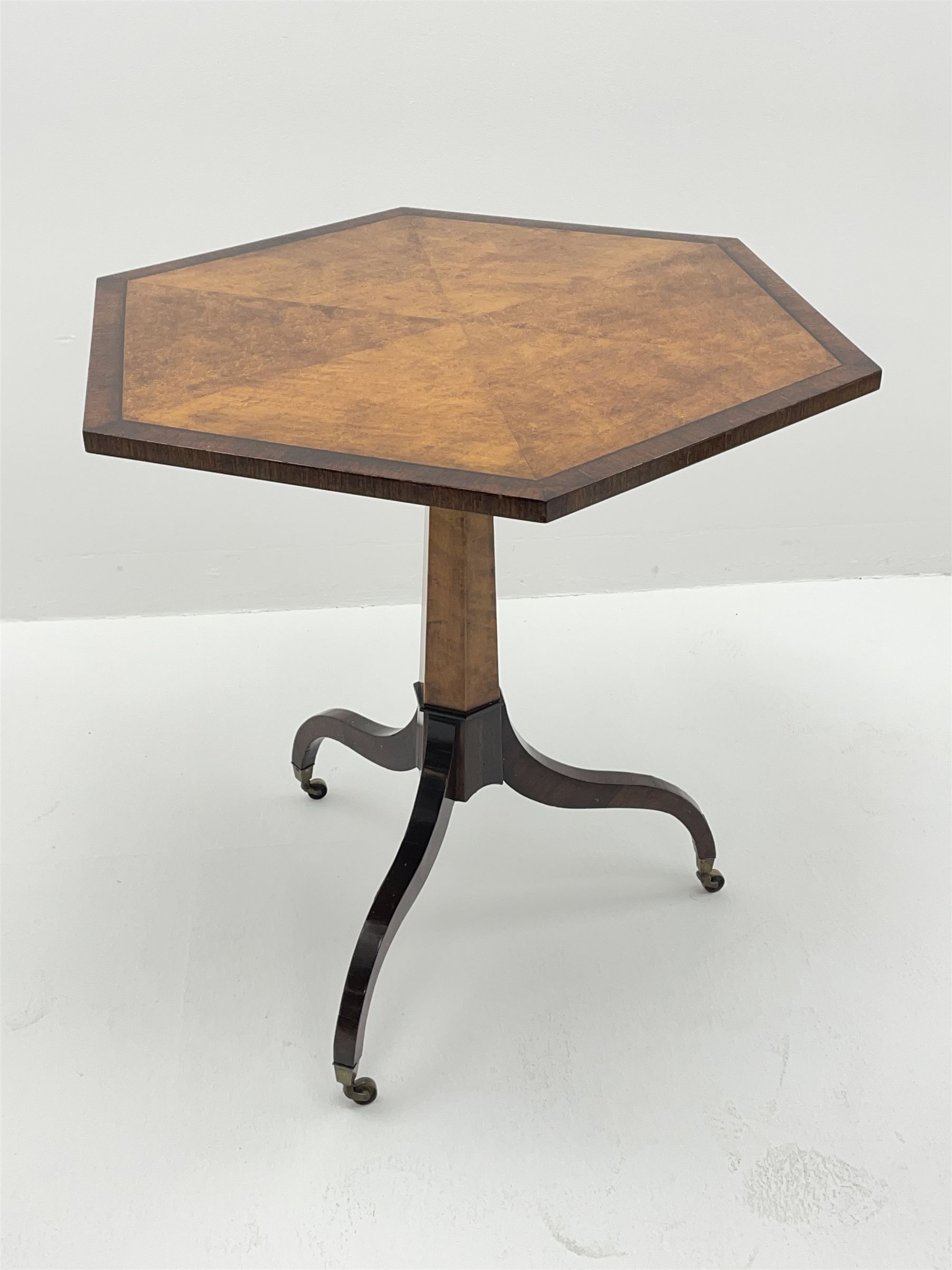Regency style birdseye maple and rosewood tripod table, hexagonal tilt top with segmented veneer and banding, tapered hexagonal column on three splayed serpentine supports, brass cups and castors 