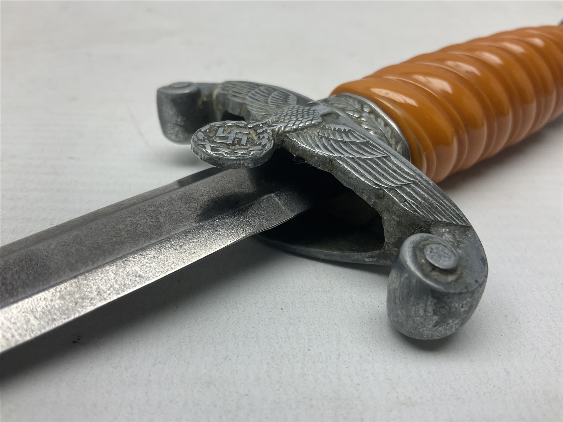 Late WW2 German Army Officers dress dagger, with unmarked 25cm double edged steel blade, orange celluloid grip, pommel and ferrule with oakleaves relief and cross guard with eagle; in original beaded scabbard with two hanging rings L39.5cm overall