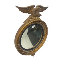 Regency design gilt famed wall mirror, eagle pediment on a rocky plateau, the circular convex plate within a reeded ebonised slip, frame decorated  with applied spheres