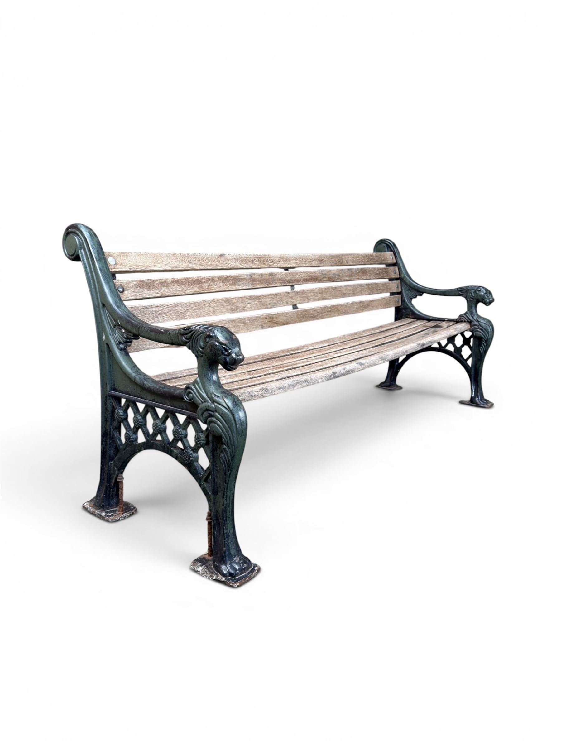 Neoclassical design cast iron and oak slatted garden bench, the twin end supports in the form of a Sphinx with acanthus carved knees and large paw feet, the pierced lattice bracket with Yorkshire rose motifs