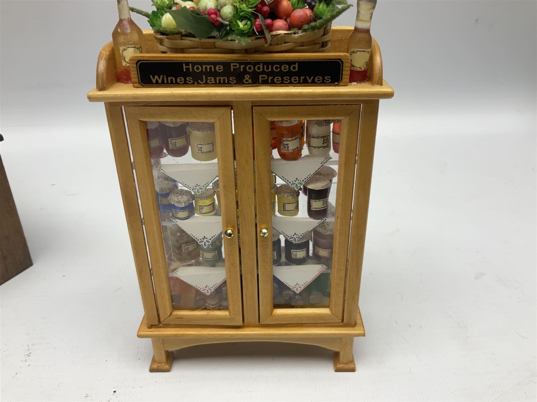 Collection of miniature dolls house grocery shop furniture and produce, comprising glazed corner counter with brass style cash register, shelved preserves unit, pies, cheese board and trays of meats, pair of white cheese counters, biscuit display with six tins, glazed preserves cabinet, pair of shop chairs and four further cheese boards complete with grapes and label flags