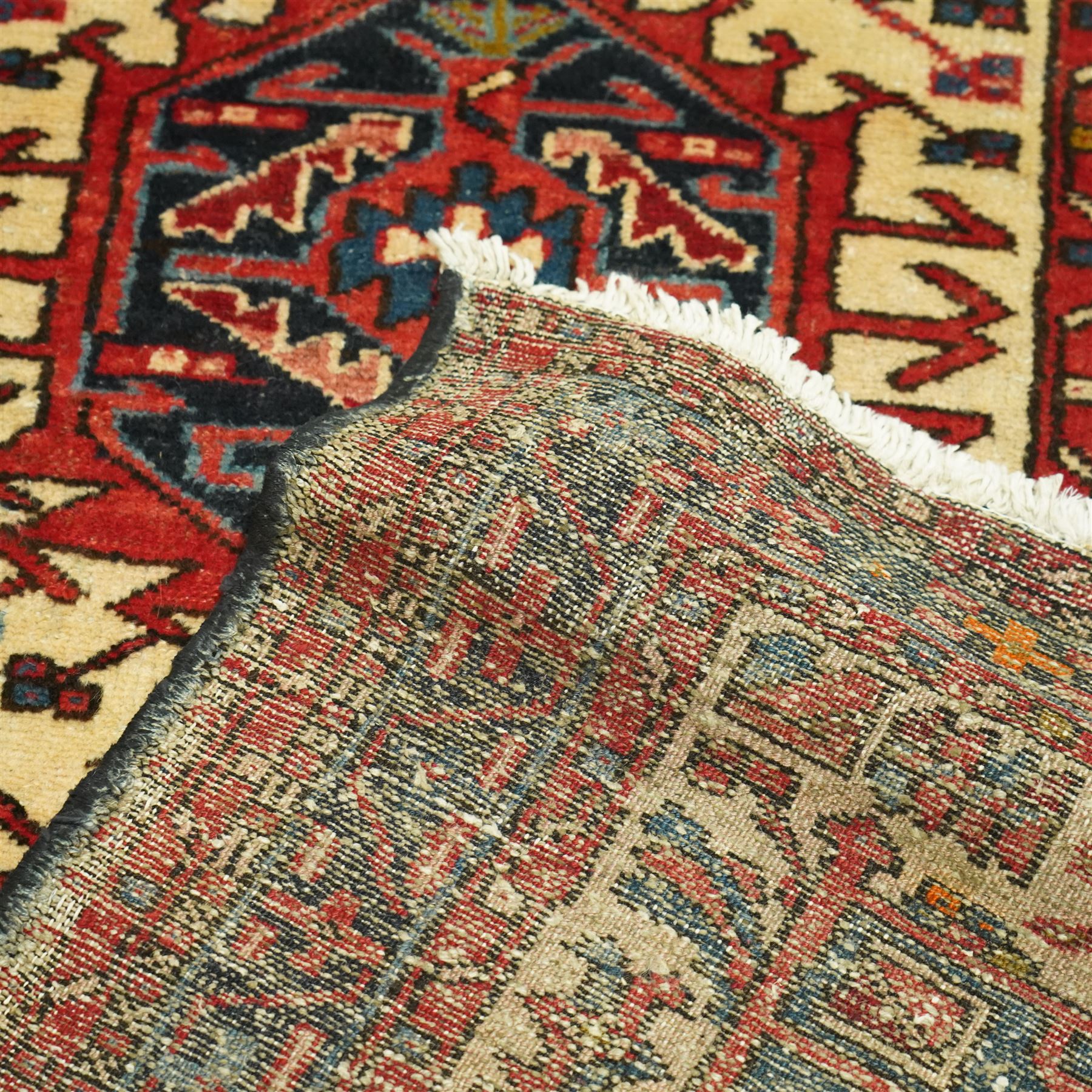 Caucasian Shirvan hand-knotted runner, ivory field decorated with a vertical sequence of bold hexagonal and lozenge medallions, each enclosing stylized geometric motifs, flanked by angular floral latch-hook devices, field dominated by madder red  and ivory with subsidiary colours of indigo, brown, and turquoise, with fringe ends   