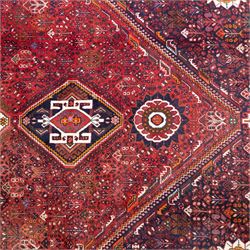 Qashqai wool carpet, red diamond-shaped field decorated with three stepped pole medallions, floral rosettes and scattered stylised motifs, within dark blue spandrels and multiple geometric guard borders