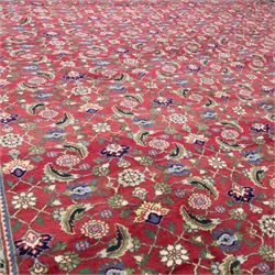 North West Persian Tabriz hand-knotted carpet, herati-type field in deep red with an all-over field densely decorated with scrolling floral sprays and palmettes on a lattice ground enclosed by a dark blue main border filled with stylized floral motifs and interlacing tendrils flanked by multiple guard stripes, with cotton fringe ends 