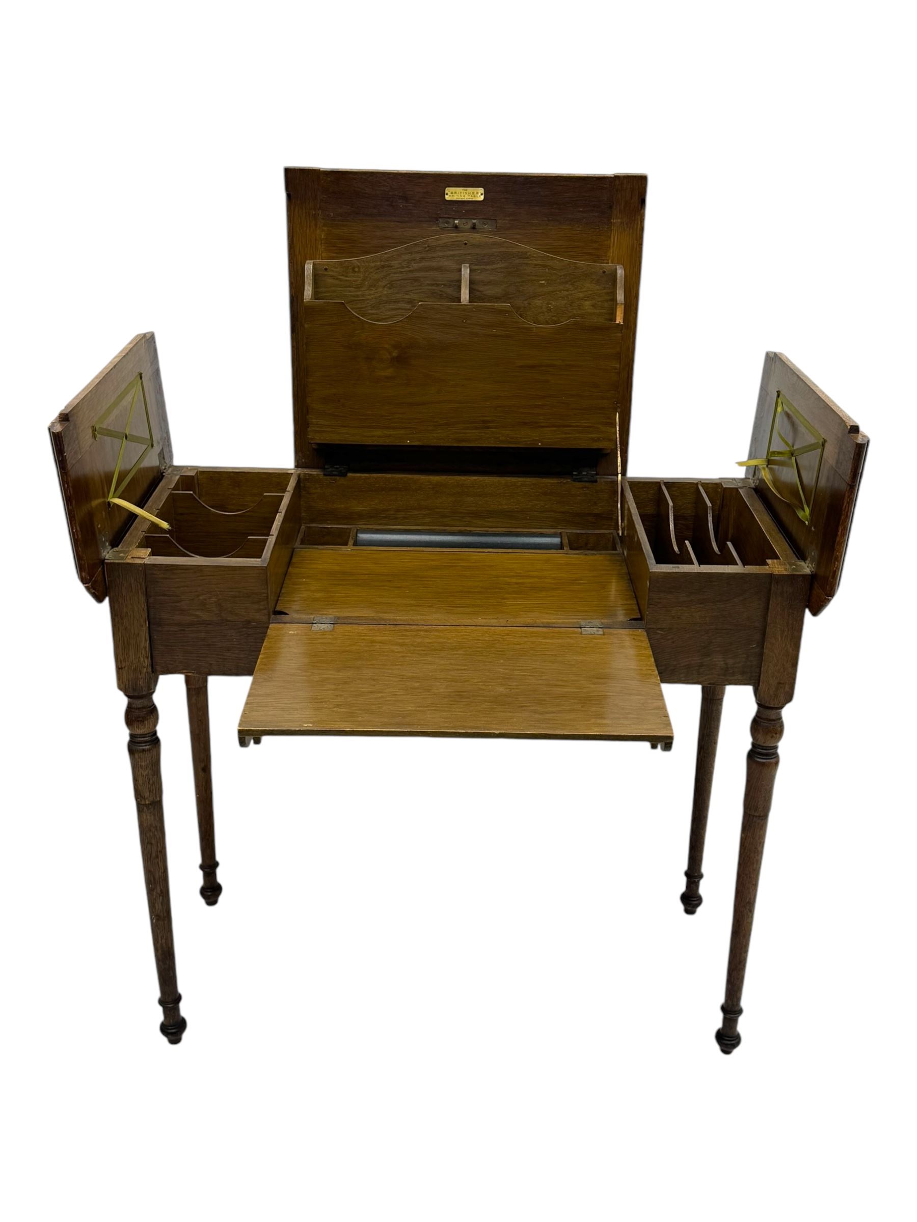 Edwardian oak metamorphic 'Britisher Writing Table', rectangular hinged top revealing correspondence compartments and hinged writing surface with underside storage, flanked by twin hinged compartments with dividers, on turned supports