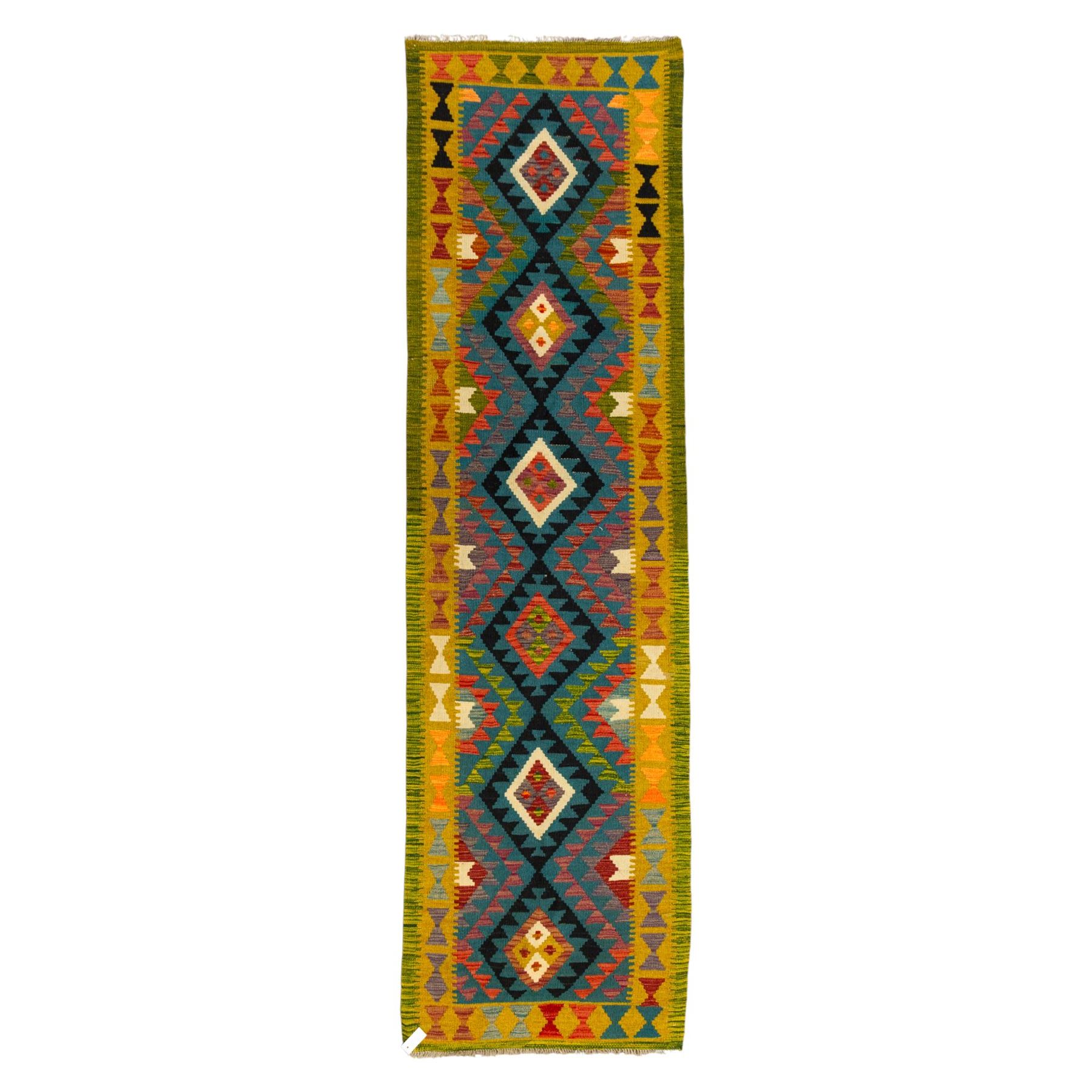 Maimana kilim flatweave runner, central field features a large bold nested diamond motif and stylized geometric lozenge patterns on olive purple, blue, and green tone ground, border stripe in teal ground, and fringe