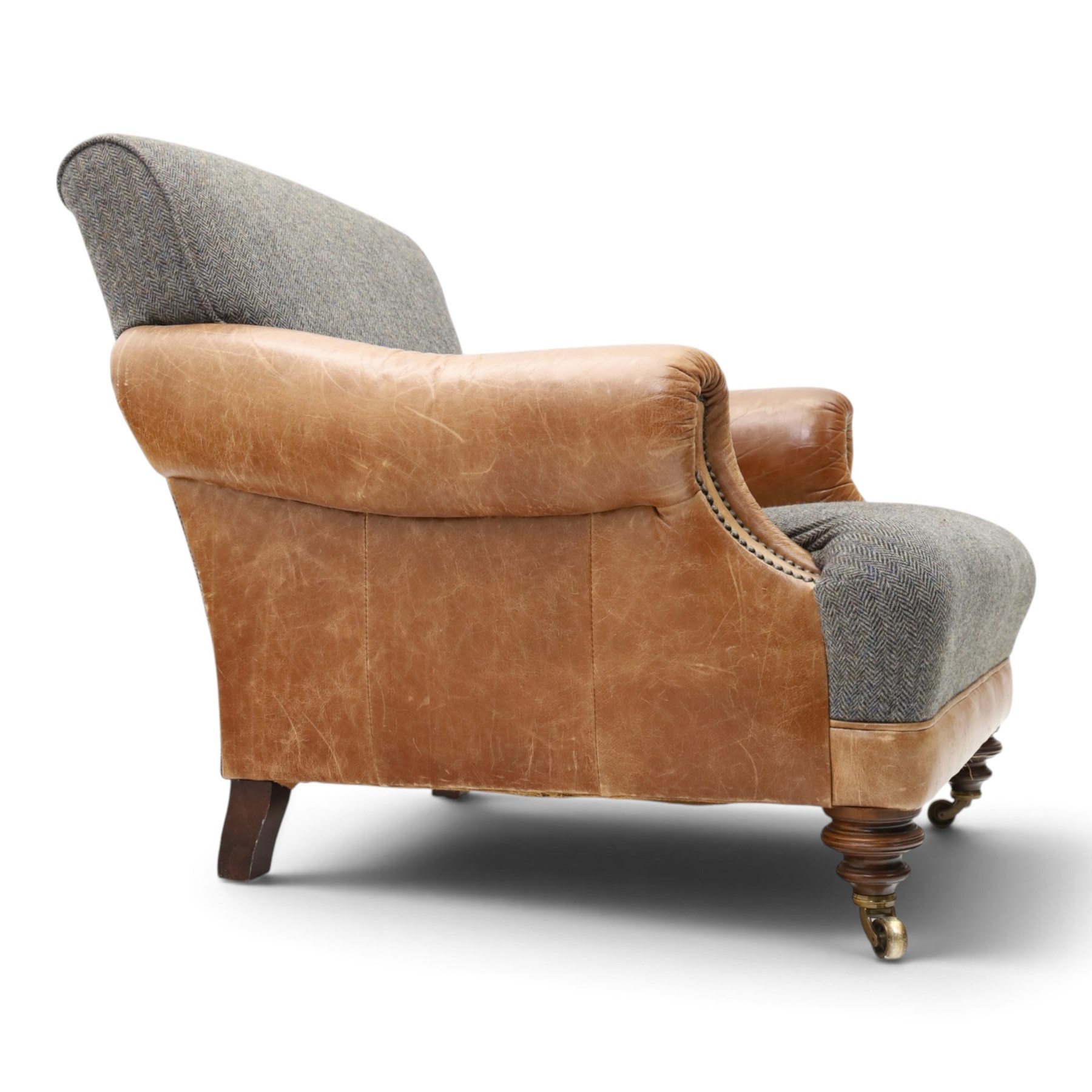 Tetrad - 'Taransay' Harris Tweed and tan leather club armchair, Howard shape with reclined back over deep seat and rolled arms with studwork, raised on turned front supports with castors, the sides and arms upholstered in tan leather with seat and back in herringbone-stitched Harris Tweed