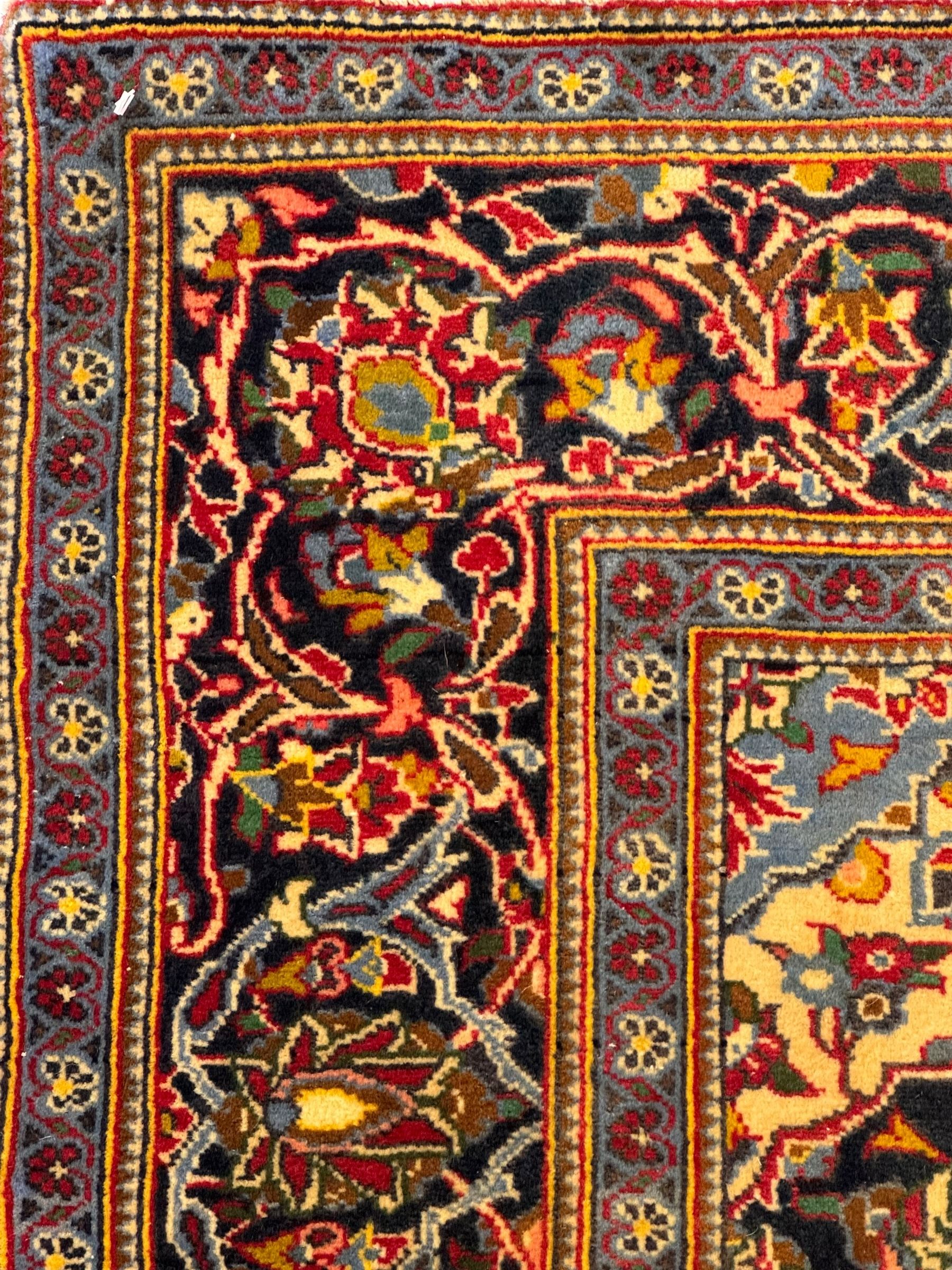 Central Persian Kashan crimson ground rug, central indigo pole medallion surrounded by sparsely placed bouquets interconnected with foliate branches, the guarded border with repeating palmette and Boteh motifs with interwoven scrolling patterns, framed by guard stripes