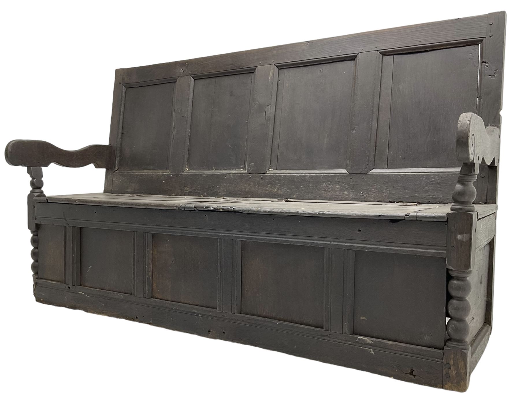 18th century oak box seat settle bench, pegged construction with quadruple panelled back over double hinged box seat, shaped projecting arms with scroll carved terminal detail, on block and bobbin turned front supports, panelled front within moulded frame