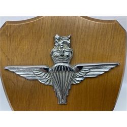 Parachute regiment - chrome crest on oak easel shield; three cloth badges; small silver plated figure; and pin badge; together with 10cm diameter cannon ball etc