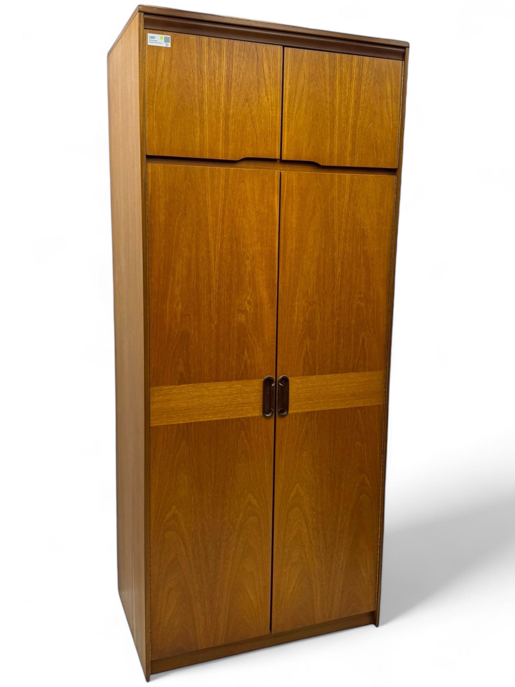 William Lawrence - mid-20th century teak double wardrobe, upper storage section over twin doors featuring recessed handles and contrasting horizontal panel, enclosing a hanging rail compartment, on plinth base with concealed castors