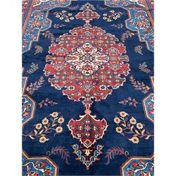 Persian Veis indigo ground carpet, the field with large pole medallion decorated with Herati motifs and surrounded by floral sprays, crimson ground border with repeating cross motifs and stylised flower heads, within guard stripes 